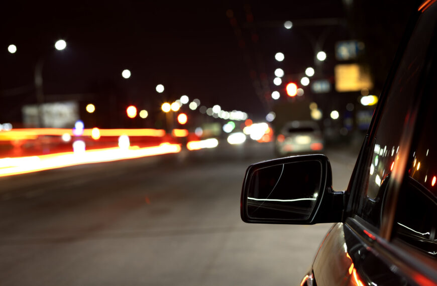 Spiegelung der Straßenbeleuchtung am Auto bei Nacht